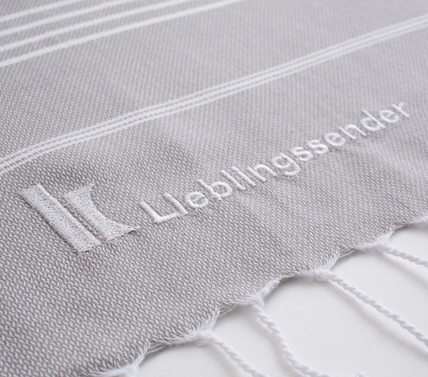 Klassik Radio Hamamtuch, rangezoomz mit eingestickten K von Klassik Radio-Logo und dem Wort Lieblingssender