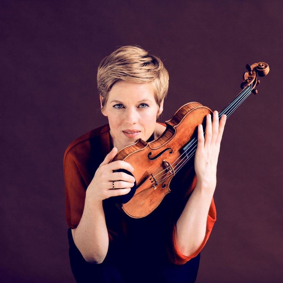 Portrait von Isabelle Faust mit einer Violine in der Hand, vor lilanem Hintergrund 