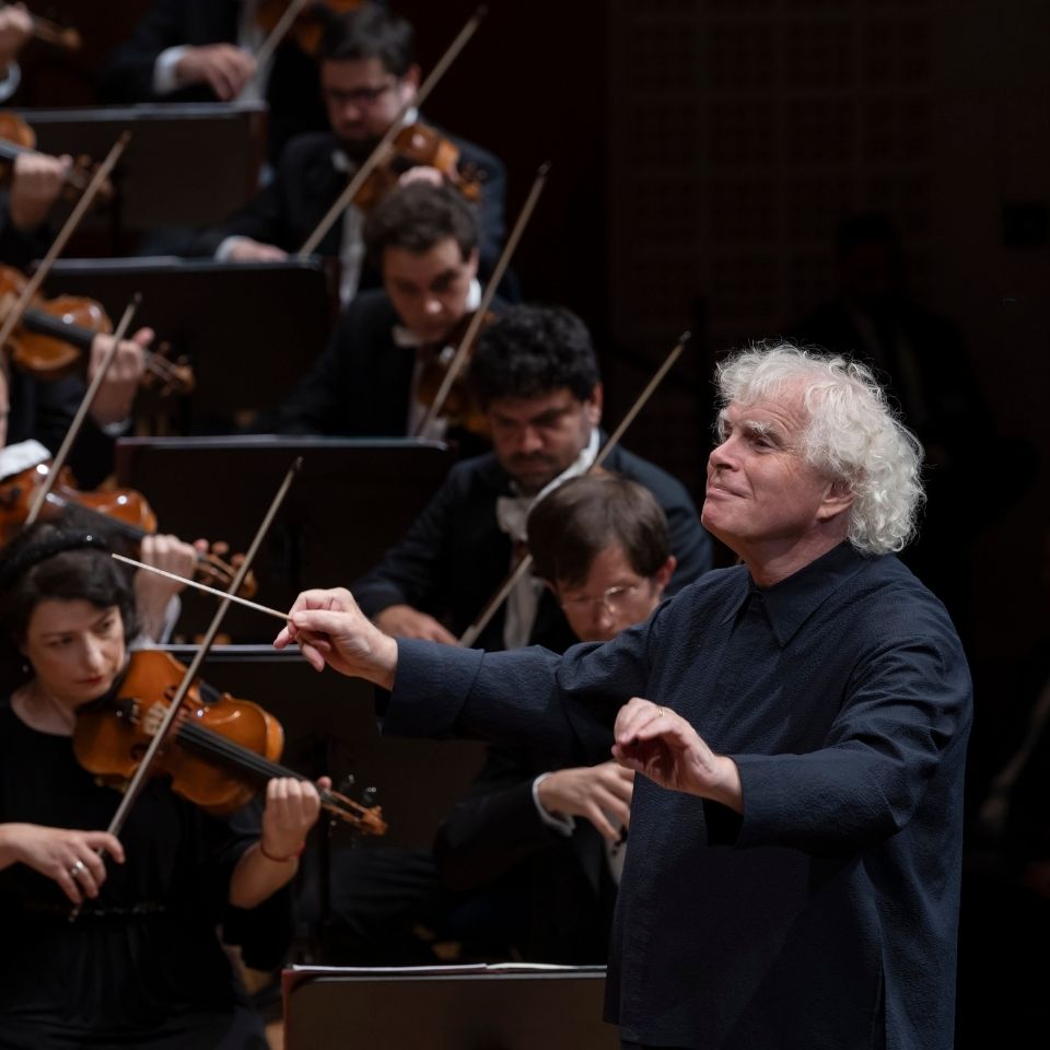Dirigent Sir Simon Rattle leitet ein Orchester beim Aufführen