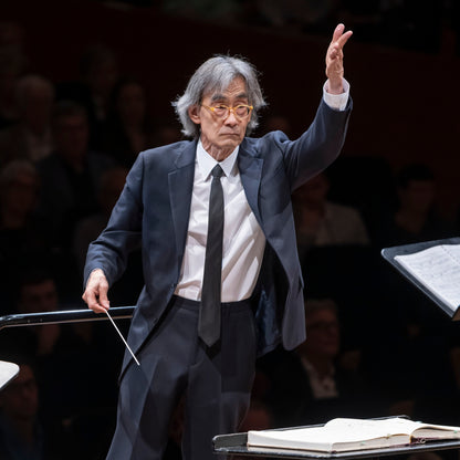 Portrait des Dirigenten Kent Nagano in einem dunkelblauen Anzug beim Dirigieren während eines Konzerts