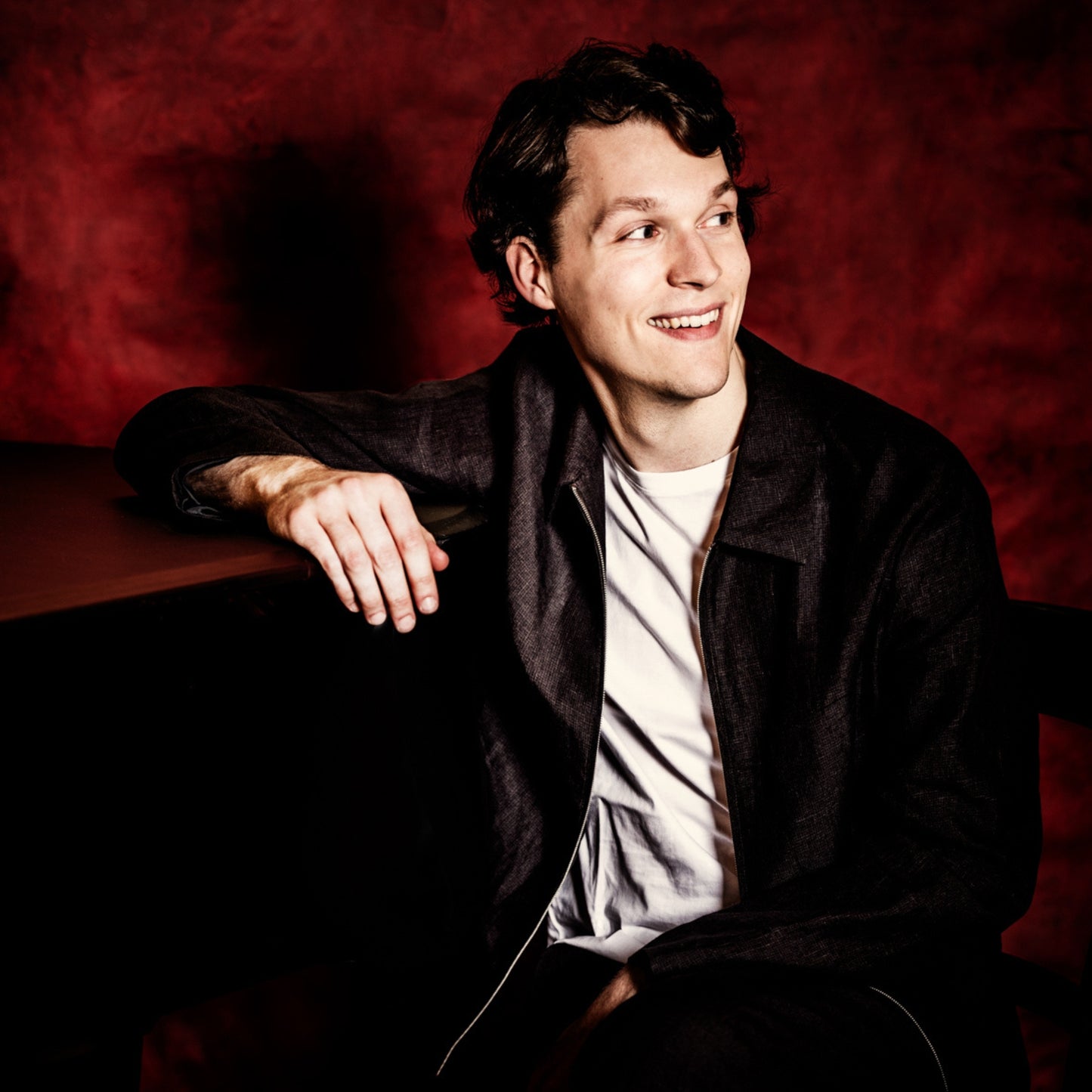 Portrait des Pianisten Lukas Sternat vor rotem Hintergrund